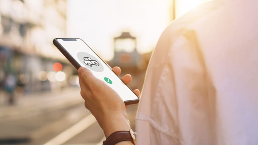 A person holds a phone and is looking at a rideshare service