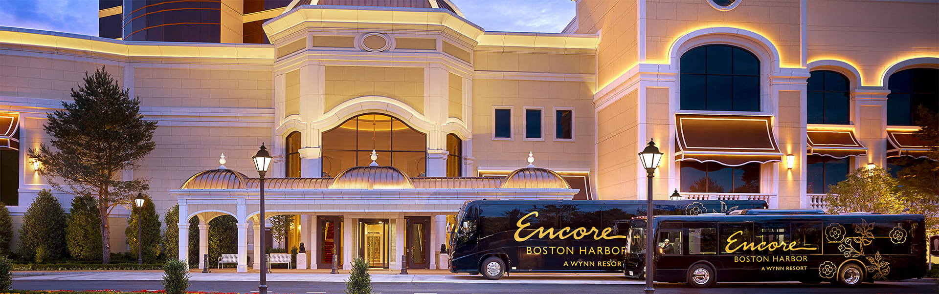 Two Encore Boston Harbor shuttles sit in front of the exterior of the building