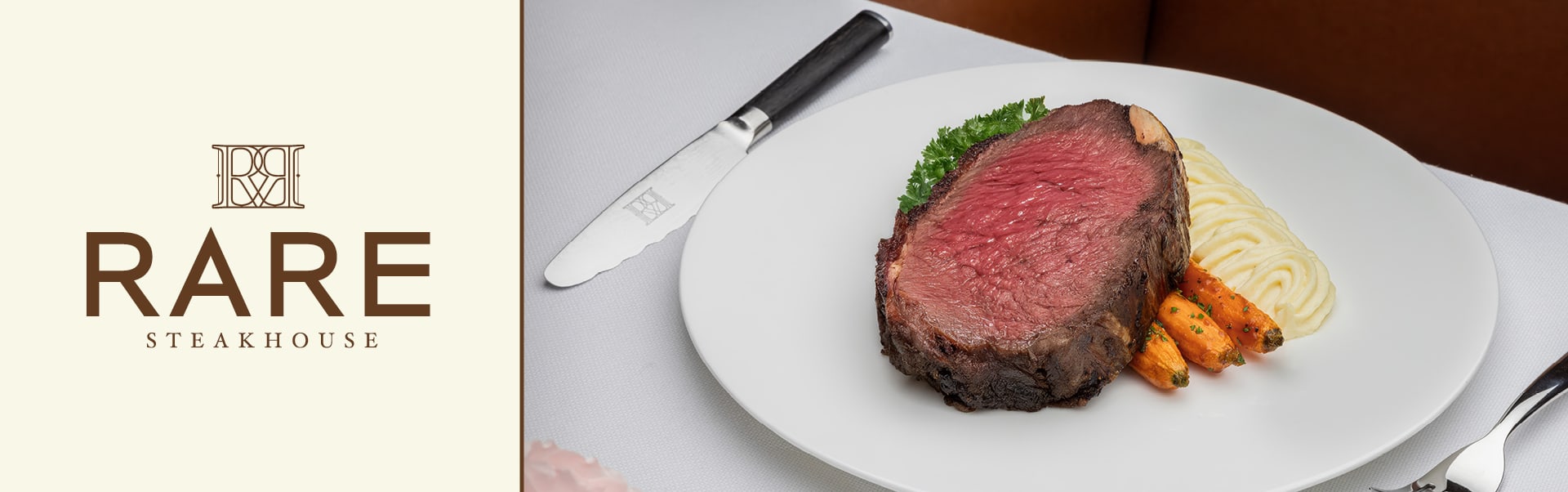 A slice of prime rib sits on a bed of mashed potatoes and carrots on a white plate