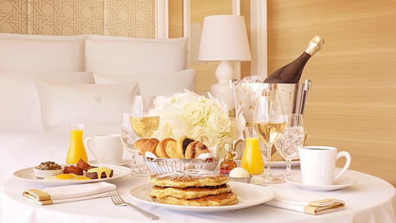 Various in-room dining breakfast items are shown on a table