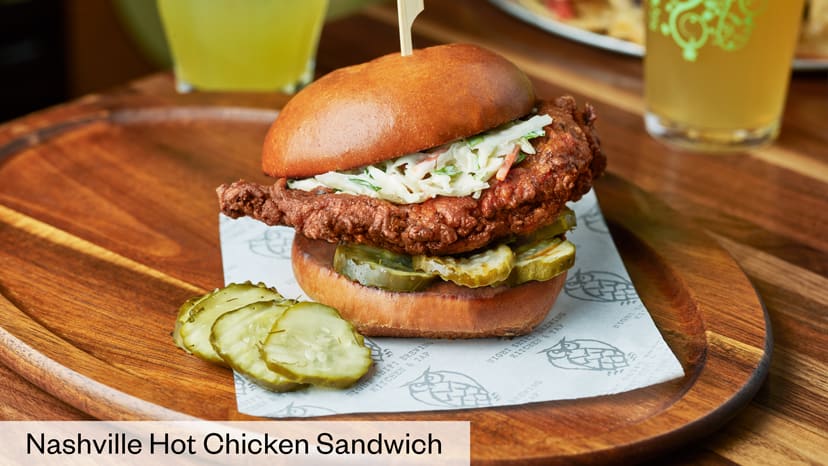 A chicken sandwich shown with pickles and cole slaw